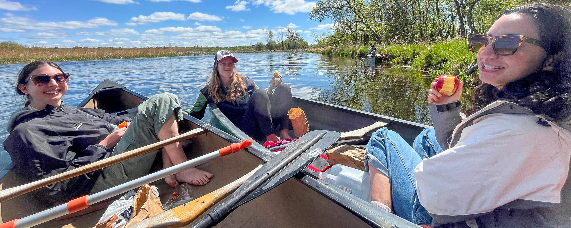 Students smiling in canoes on a lake.